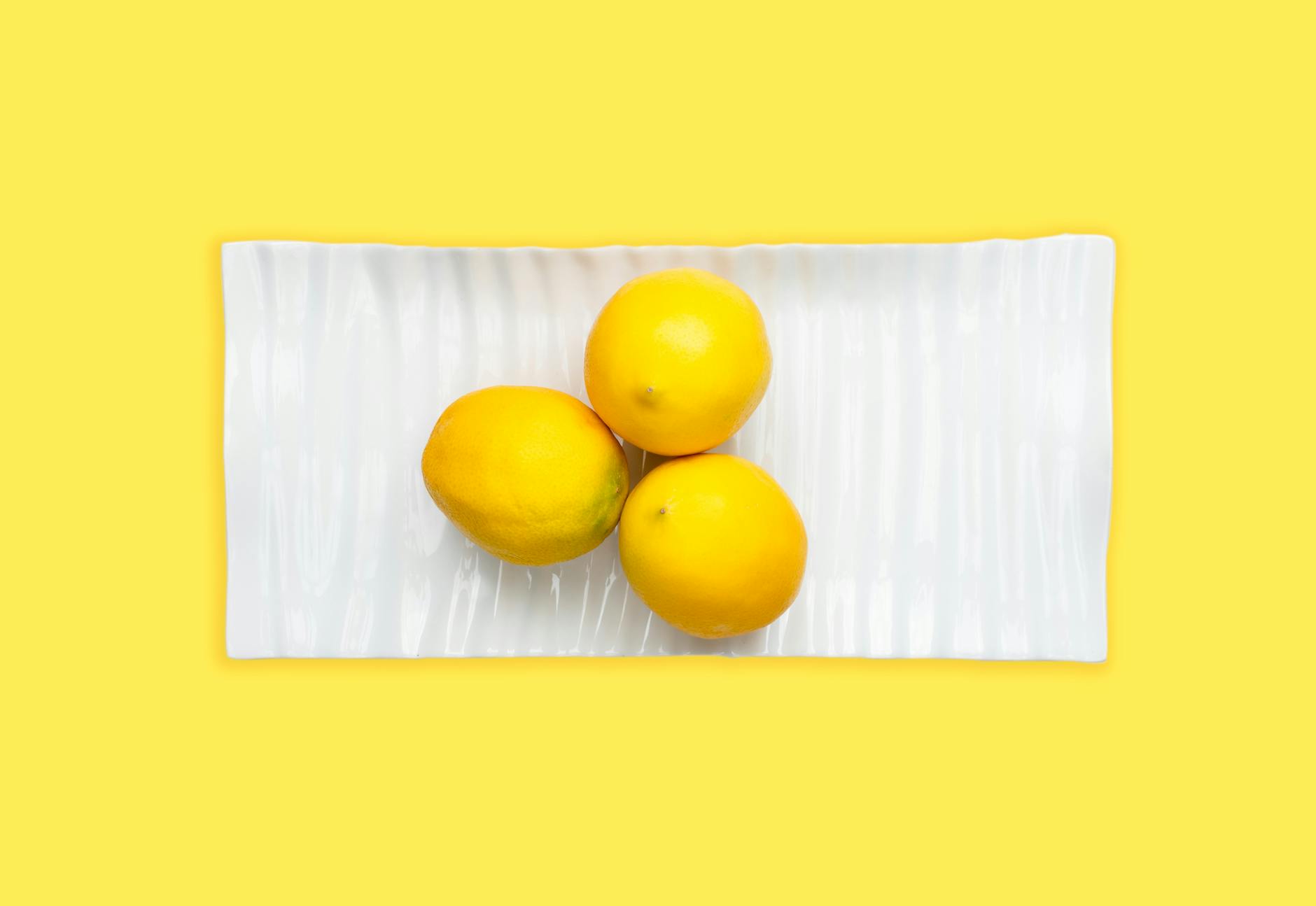 A blue vibrator surrounded by flowers and citrus slices on a bright yellow background, symbolizing renewal and vibrant pleasure.
