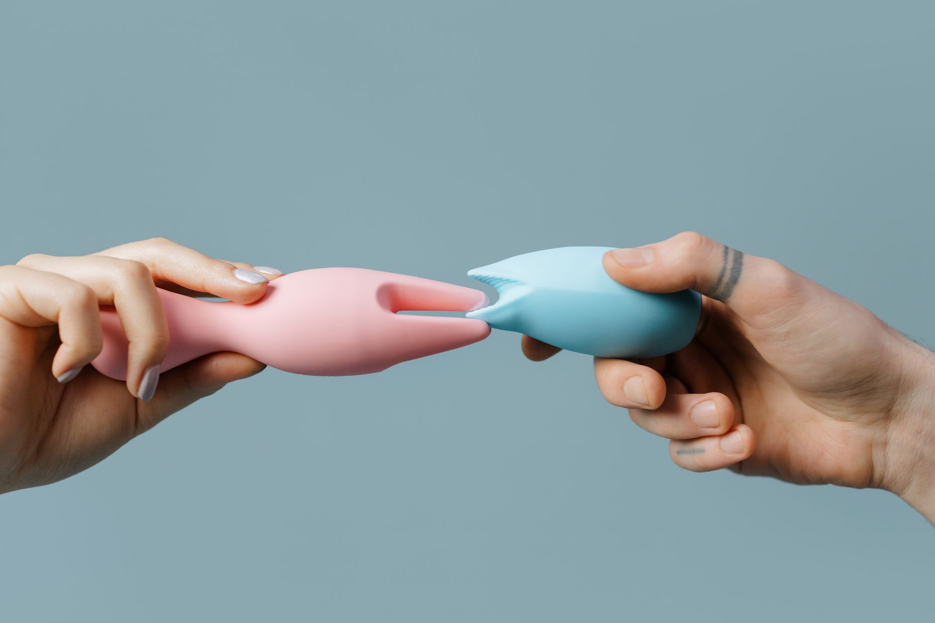 Hand holding a pastel silicone vibrator against a soft background