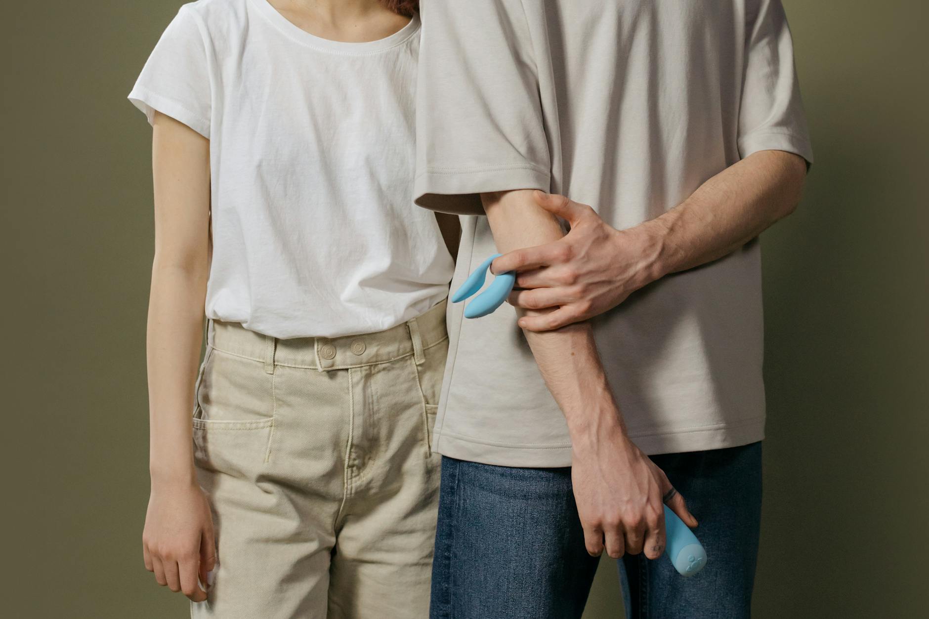 A close-up of a hand holding an orange vibrator against a minimalistic purple backdrop, showcasing modern sensuality.