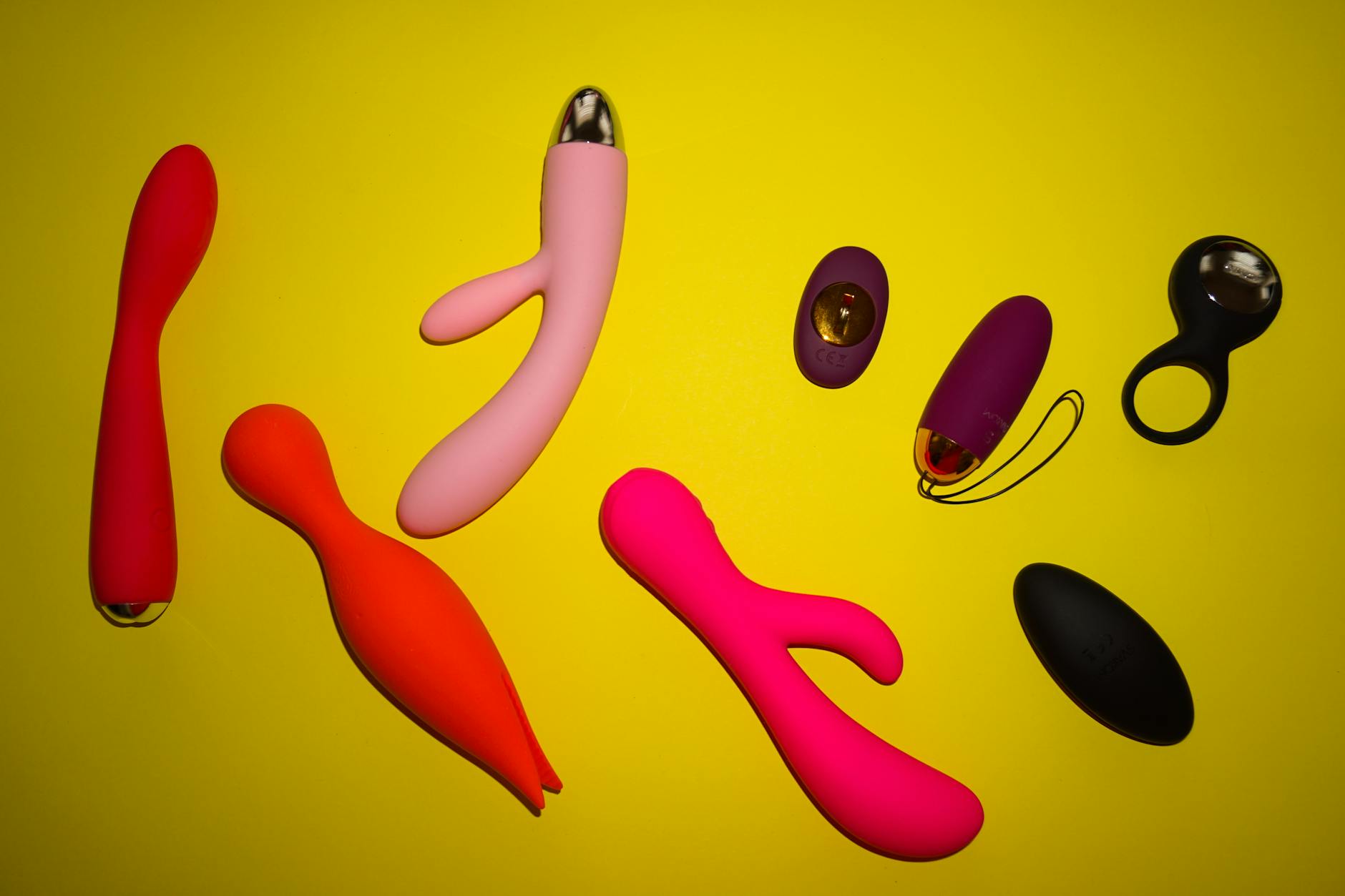 Close-up of hands holding a sleek blue clitoral vibrator against a purple background