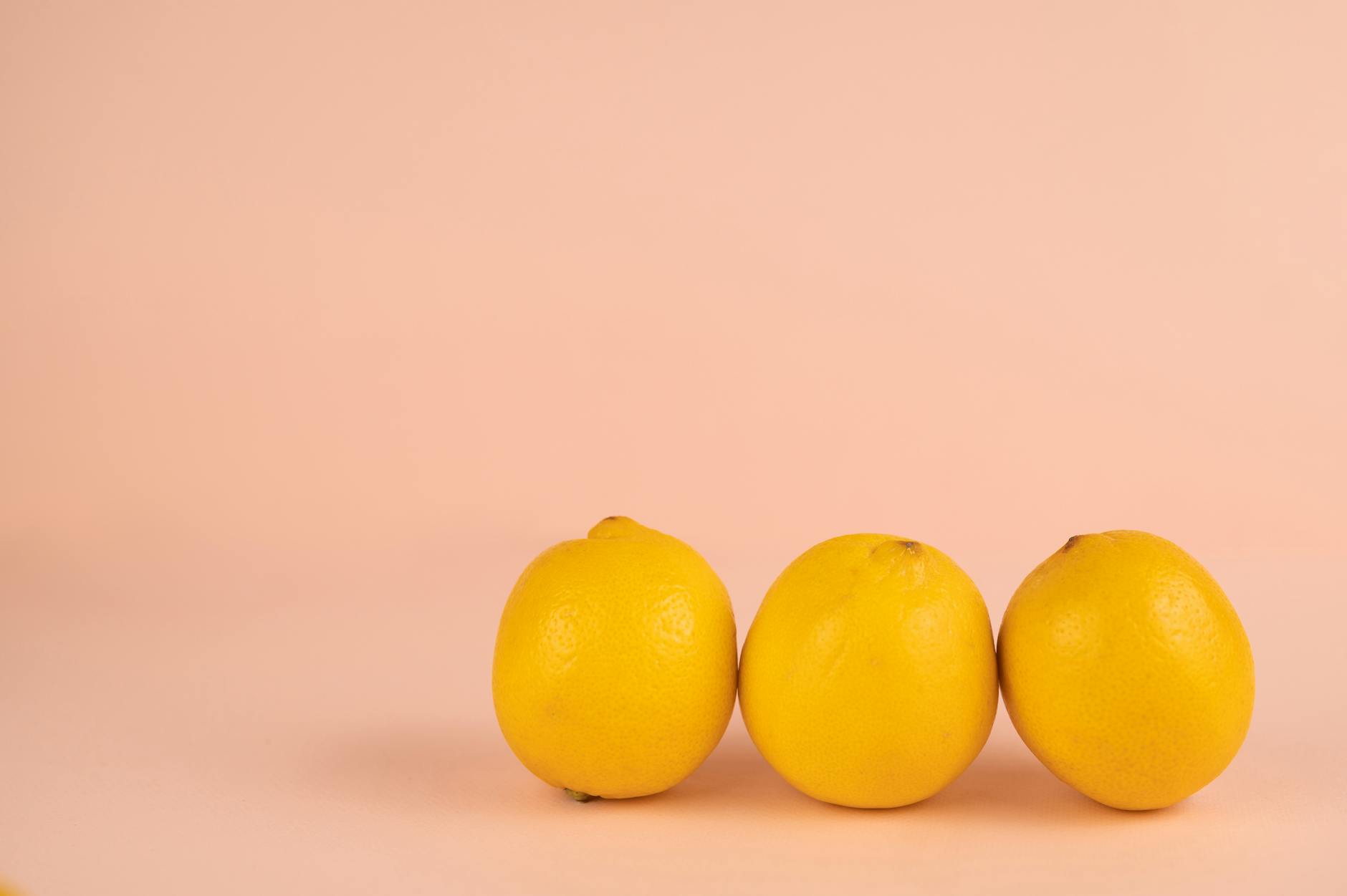 Three fresh lemons on a white plate against a vibrant yellow background, symbolizing vitality and renewal