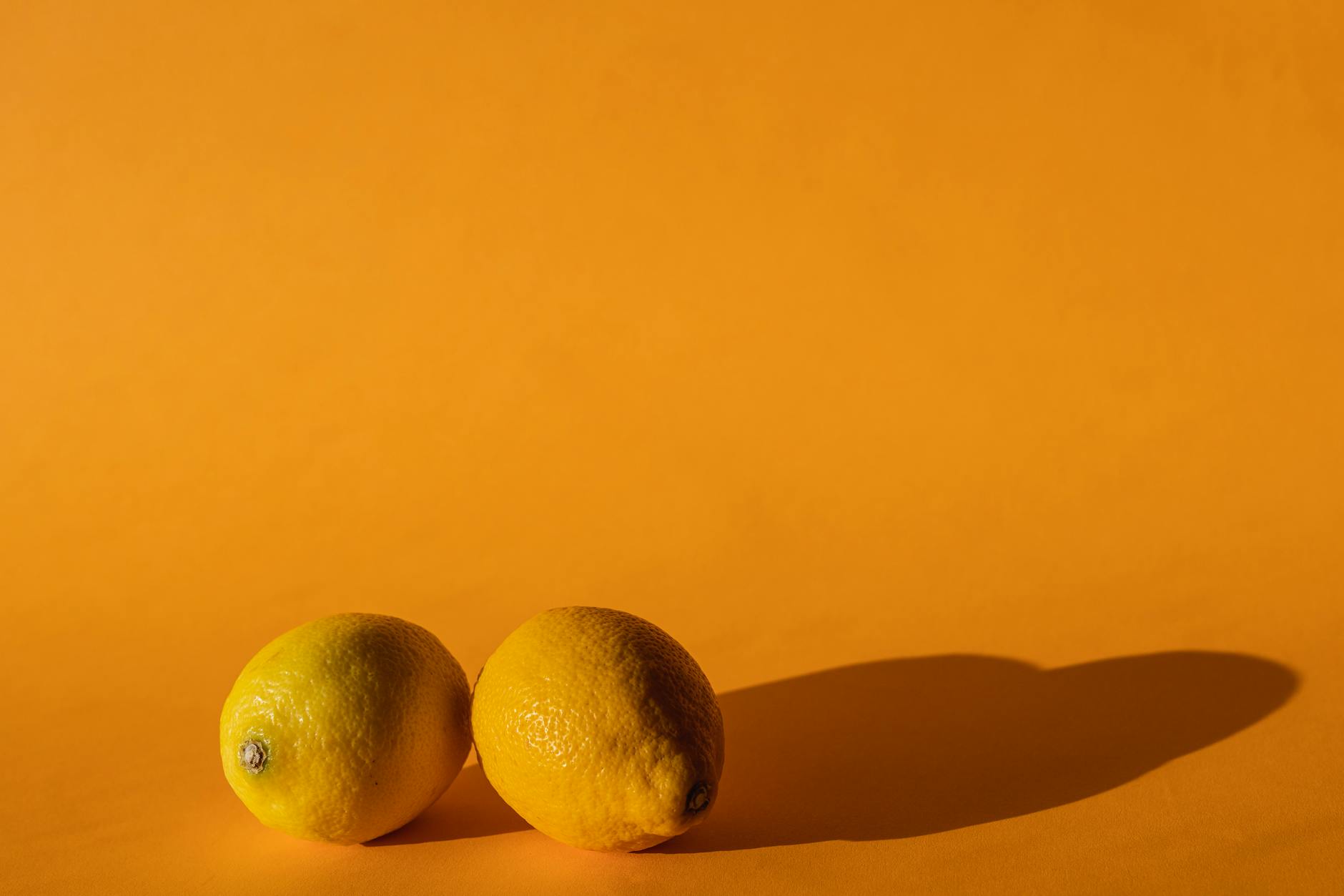 A yellow silicone vibrator surrounded by fresh fruit on a bright background